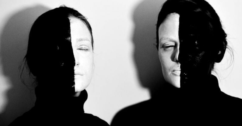 Color Psychology - Black and white of models with face covered with black and white paints standing with closed eyes against white background