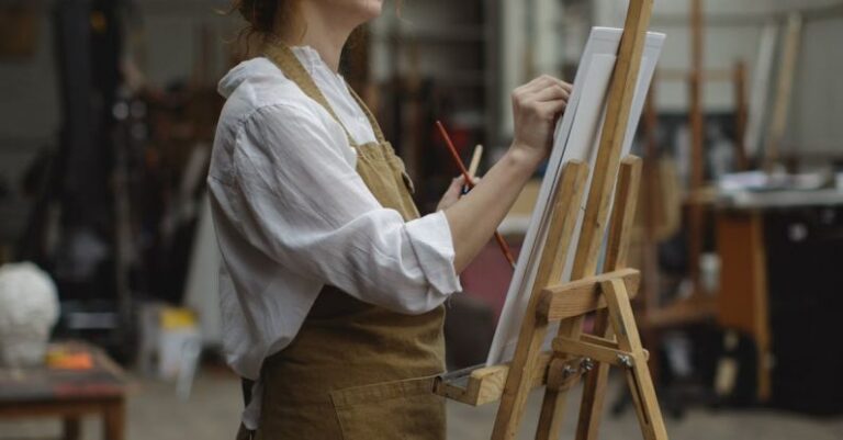 Visual Narratives - Young Woman in Brown Apron Sketching on White Cardboard