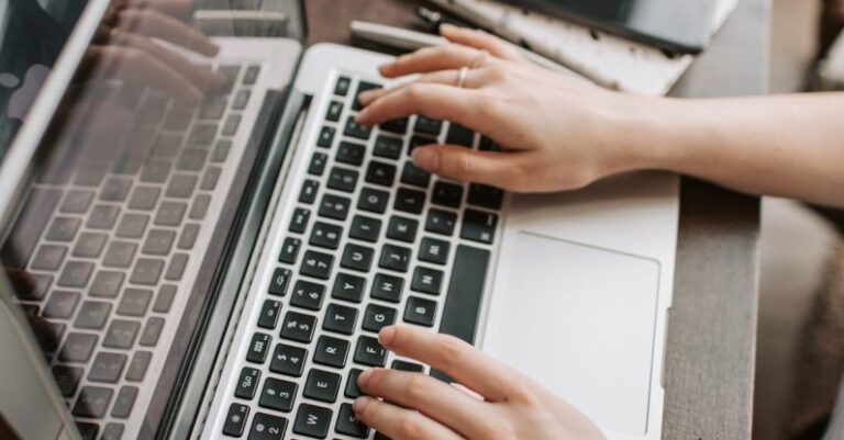 Information Retention - From above of unrecognizable woman sitting at table and typing on keyboard of computer during remote work in modern workspace