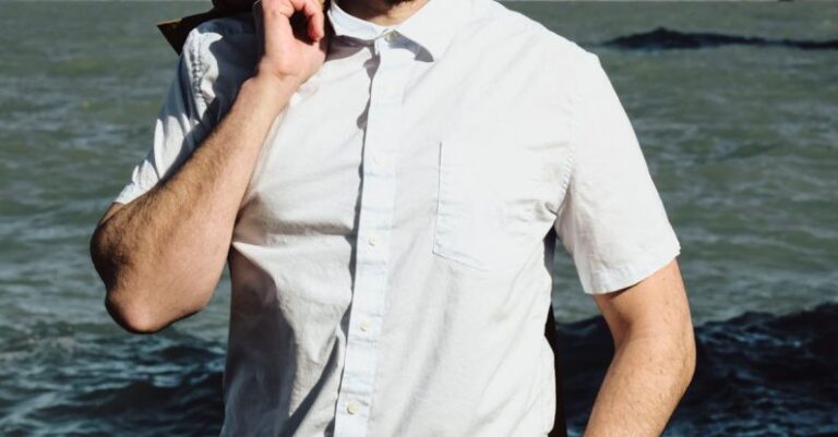 User Satisfaction - A man in a hat and shirt standing by the water