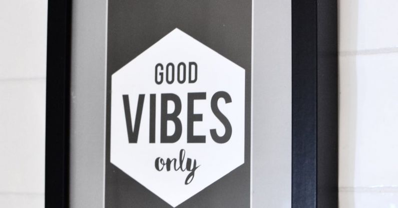 Typography Elements - Picture in wooden frame with Good Vibes Only inscription hanging on white tiled wall